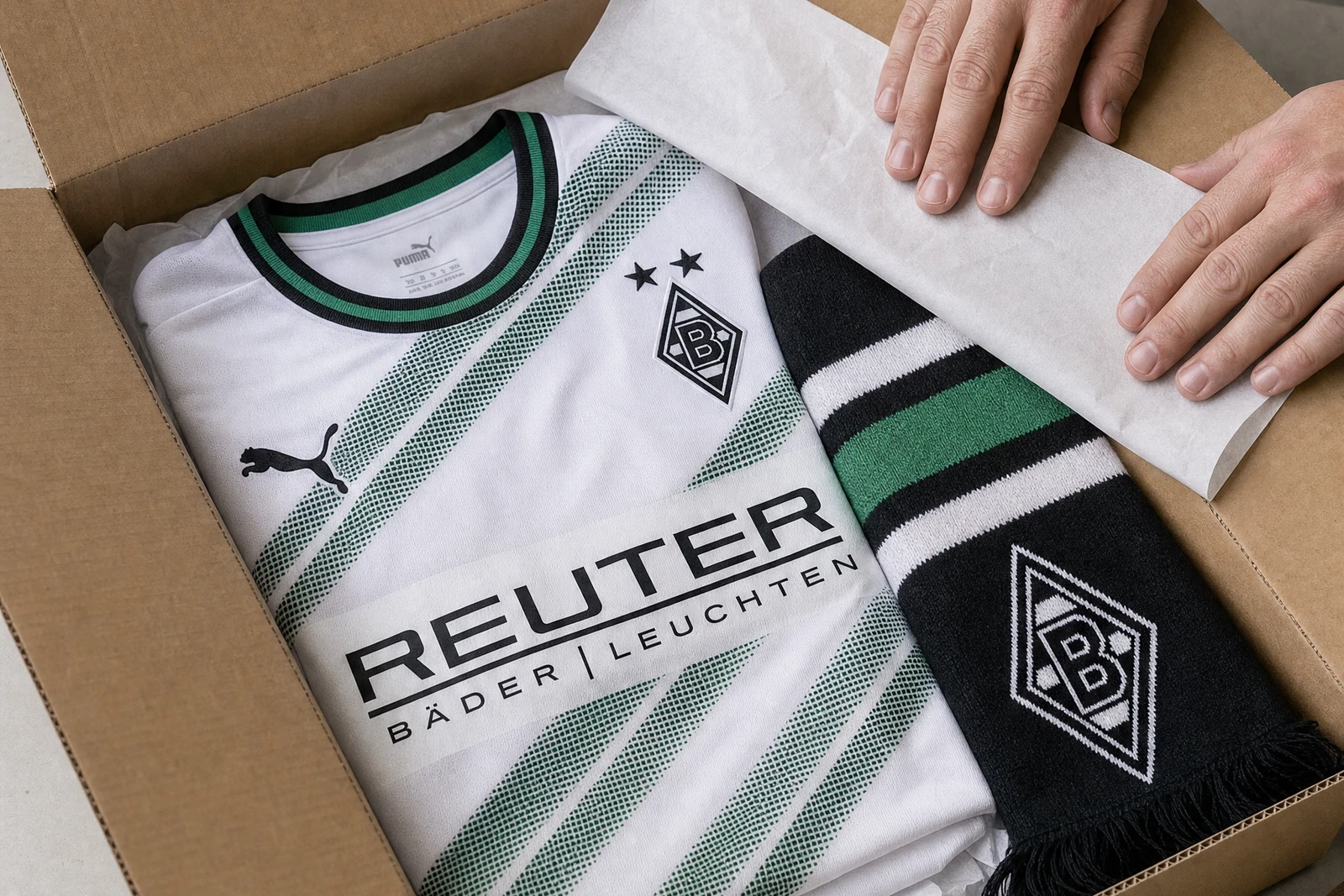 Ein weiß-grünes Borussia-Mönchengladbach-Trikot und ein Fanschal liegen geschützt im Versandkarton.